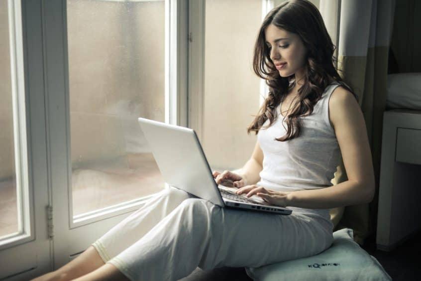 Woman sitting in window on laptop